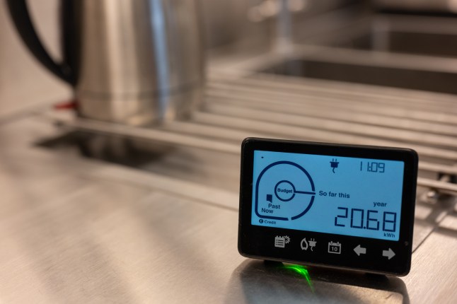 Home electricity smart meter in kitchen and stainless steel kettle.