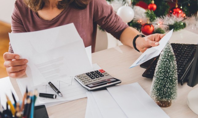 Woman sitting at the office desk and reading letter with christmas tree in the background