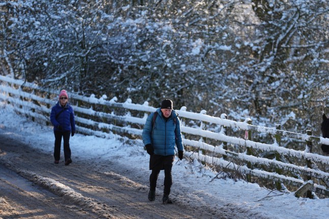 People walk through snow in Balerno, Edinburgh. The UK Health Security Agency (UKHSA) has issued cold weather health alerts for all of England ahead of a week of low temperatures. Amber alerts have been issued from 12pm on Thursday until January 8, meaning a rise in deaths, particularly among those aged 65 and over or with health conditions, is likely, the UKHSA said. Picture date: Friday January 3, 2025. PA Photo. Photo credit should read: Andrew Milligan/PA Wire