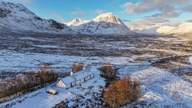 GLENCOE, SCOTLAND - JANUARY 08: A walker passes Black Rock Cottage in front of Buachaille Etive Mor on January 08, 2025 in Glencoe, United Kingdom. The Met Office has issued weather warnings as a cold snap sweeps across the UK, bringing bouts of ice, snow, and rain. (Photo by Jeff J Mitchell/Getty Images)