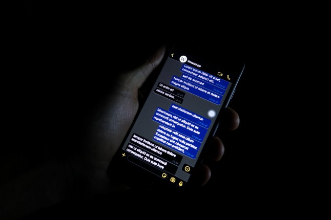 Turin, ITALY- October 10, 2019: Person holding a phone displaying a possible look of the dark mode of WhatApp, the popular message application.; Shutterstock ID 1525754270; purchase_order: -; job: -; client: -; other: -