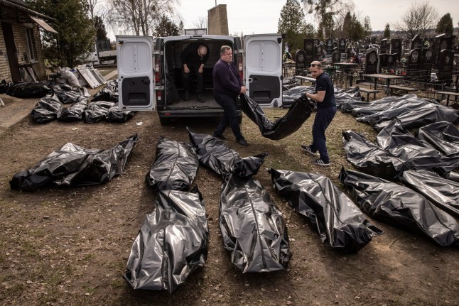 BUCHA, UKRAINE - APRIL 07: (EDITORS NOTE: Image contains graphic content) Cemetery workers unload bodies of civilians killed in and around Bucha before they are transported to the morgue at a cemetery on April 07, 2022 in Bucha, Ukraine The Ukrainian government has accused Russian forces of committing a "deliberate massacre" as they occupied and eventually retreated from Bucha, 25km northwest of Kyiv. Hundreds of bodies have been found in the days since Ukrainian forces regained control of the town. (Photo by Chris McGrath/Getty Images)