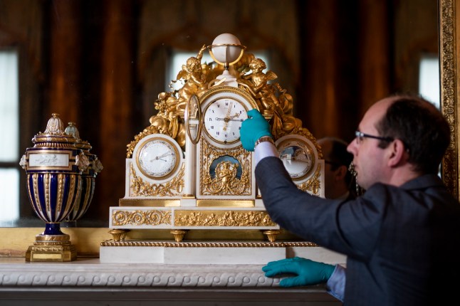 EMBARGOED TO 2230 FRIDAY MARCH 24 Tjeerd Bakker, Senior Horological Conservator at Buckingham Palace, changes the time on a mantel clock c.1790 created by Jean Antoine Lepine (1720-1814) made from Carrara marble, gilt bronze, enamel, blued steel in the Blue Drawing Room at Buckingham Palace in London, in preparation for moving forward an hour to British Summer Time (BST) on Sunday. Picture date: Thursday March 23, 2023. PA Photo. Photo credit should read: Aaron Chown/PA Wire