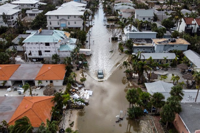 TOPSHOT - In this aerial photo, a vehicle drives though a flooded street after Hurricane Milton, in Siesta Key, Florida, on October 10, 2024. At least 10 people were dead after Hurricane Milton smashed into Florida, US authorities said October 10, 2024, after the monster weather system sent tornados spinning across the state and flooded swaths of the Tampa Bay area. (Photo by CHANDAN KHANNA / AFP) (Photo by CHANDAN KHANNA/AFP via Getty Images)