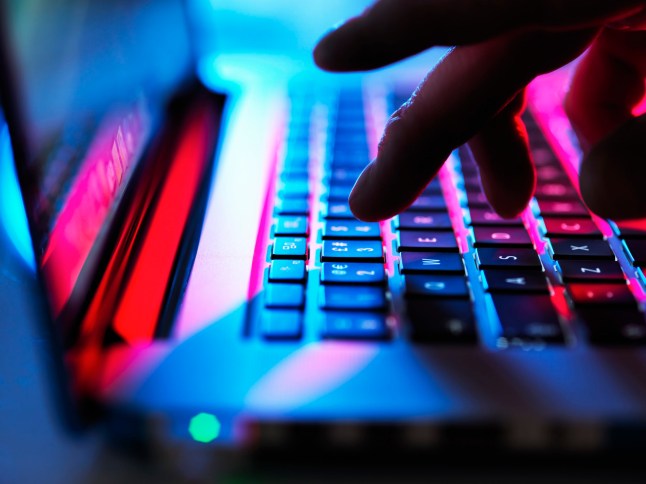 A person typing on a laptop in a dark room.