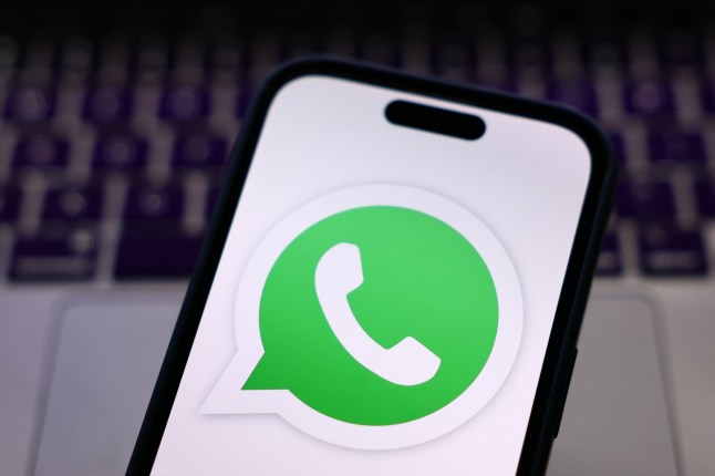 A laptop keyboard and WhatsApp logo displayed on a phone screen are seen in this illustration photo taken in Krakow, Poland on March 12, 2025. (Photo by Jakub Porzycki/NurPhoto via Getty Images)