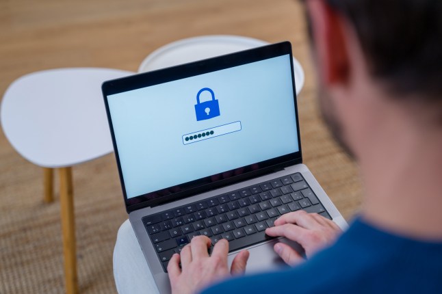 Close-up of a man's hands typing a password on a laptop keyboard, with a blue lock icon displayed on the screen, emphasizing online security
