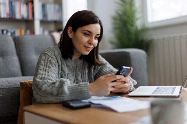 Smiling woman checking her phone while working from home