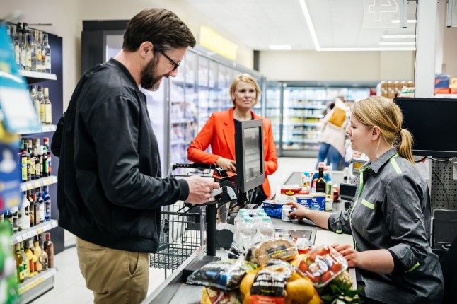 A mature man and his wife paying for their groceries at the checkout in their local supermarket.