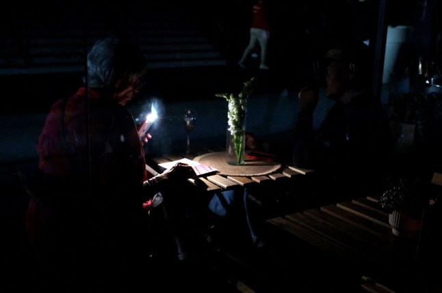 A woman uses her cell phone's flashlight in the dark after the matches get suspended due to a power outage