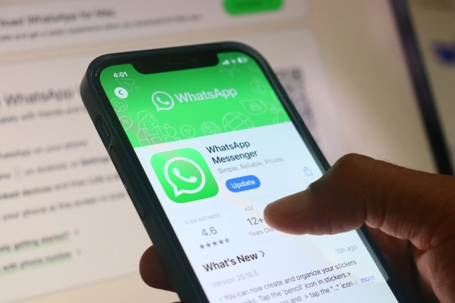 Hand holding iphone with Whatsapp messenger app.