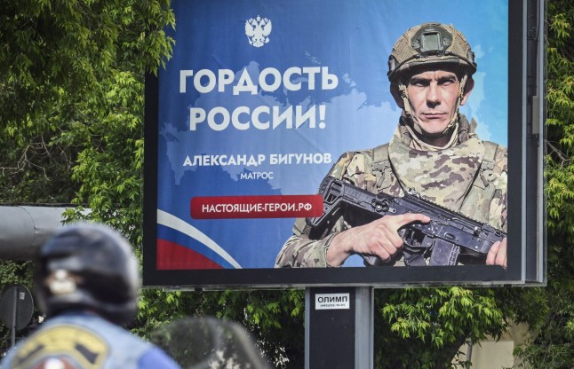 A woman walks past a poster reading "Proud of Russia" and displaying Russian Navy Sailor - Alexander Bigunov, participating in Russia's military action in Ukraine, in central Moscow on June 3, 2025. (Photo by Alexander NEMENOV / AFP) (Photo by ALEXANDER NEMENOV/AFP via Getty Images)