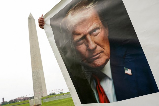 A supporter of U.S President Donald Trump holds a banner with his picture near the Washington Monument, ahead of the upcoming U.S. Army 250th anniversary celebration parade, in Washington, D.C., U.S., June 13, 2025. REUTERS/Nathan Howard
