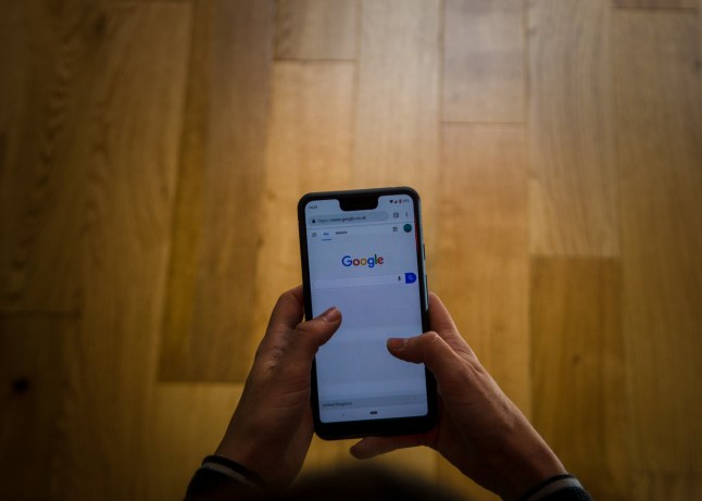 A close up shot of a person using the google pixel phone in a canid scene against a clean background.