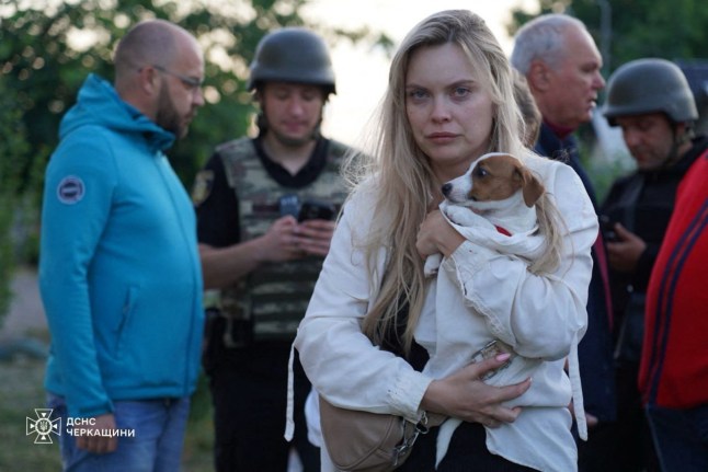 This handout photograph taken and released by the State Emergency Service of Ukraine on June 29, 2025, shows a local resident holding her dog at a site of a Russian attack in the city of Smila, Cherkasy region amid the Russian invasion of Ukraine. (Photo by Handout / Ukrainian State Emergency Service / AFP) / RESTRICTED TO EDITORIAL USE - MANDATORY CREDIT "AFP PHOTO / State Emergency Service of Ukraine" - NO MARKETING NO ADVERTISING CAMPAIGNS - DISTRIBUTED AS A SERVICE TO CLIENTS (Photo by HANDOUT/Ukrainian State Emergency Service/AFP via Getty Images)