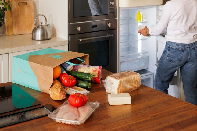 A bag of groceries ordered from Deliveroo in a kitchen, being unpacked