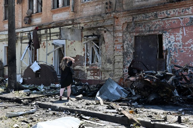 A woman stands among debris next to a recruitment centre building damaged after a drone attack in Kharkiv on July 7, 2025, amid the Russian invasion of Ukraine. (Photo by SERGEY BOBOK / AFP) (Photo by SERGEY BOBOK/AFP via Getty Images)