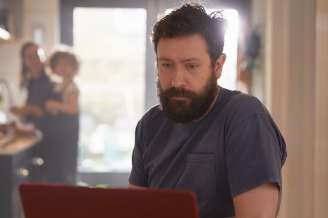 Man looking at laptop in kitchen