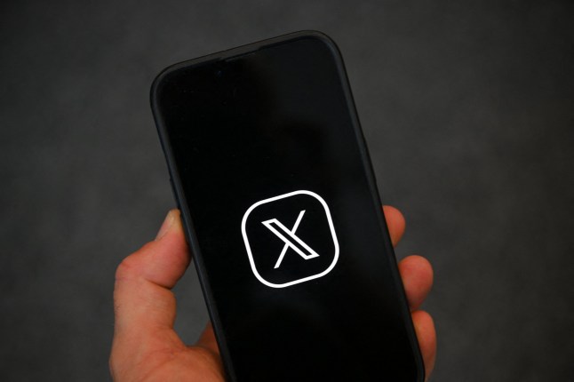 (FILES) This illustration photograph shows the logo of social network X (formerly Twitter) displayed on a smartphone in Brussels on September 27, 2024. On July 9, 2025, the cybercrime unit of the Paris public prosecutor's office opened an investigation into the social network X and its directors, on suspicion of having biased the platform's algorithm for the purposes of foreign interference, the Paris public prosecutor announced on July 11, 2025. (Photo by Nicolas TUCAT / AFP) (Photo by NICOLAS TUCAT/AFP via Getty Images)