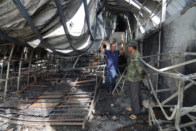 Cambodian men talk inside a damaged gas station in Phrong village, Oddar Meanchey province, Cambodia, Wednesday, July 30, 2025, after a ceasefire to end deadly border clashes was reached between Thailand and Cambodia. (AP Photo/Heng Sinith)