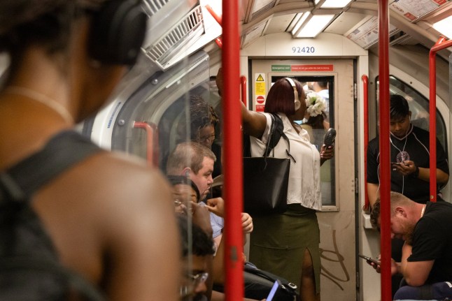 A commuter holds a handheld fan on a Central Line underground train during a heat wave in London, UK, on Monday, June 30, 2025.