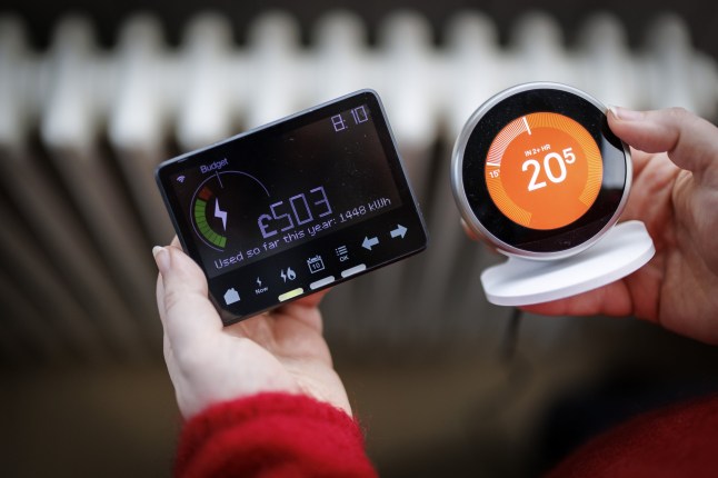 A person holding an electricity smart meter with a radiator on the background.