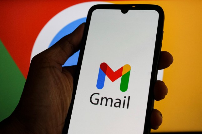 A hand holding a phone with the Gmail logo