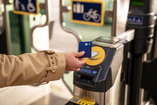 A person using a tap in payment to enter the London Underground at the ticket barrier.