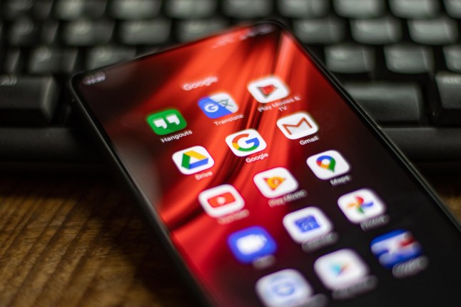 Close up photo of a mobile phone showing Google apps on the screen.