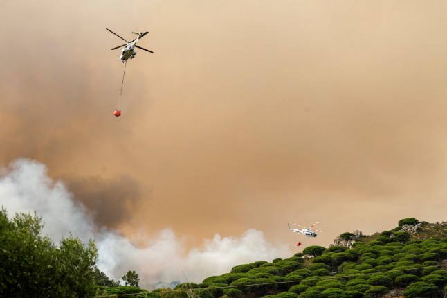 Firefighting helicopters drop water to extinguish a blaze in Torre de la Pe??a, southern Spain, Tuesday, Aug. 5, 2025. (Nono Rico/Europa Press via AP)