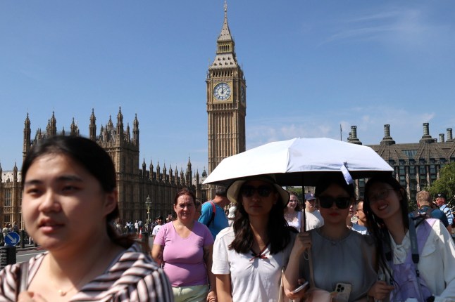 epa12293787 People shade themselves from the sun on Westminster Bridge in London, Britain, 11 August 2025. Amber heat alerts have been issued as the temperatures will continue to rise for three consecutive days, expected to reach up to 34 degrees Celsius in parts of the UK. EPA/ANDY RAIN
