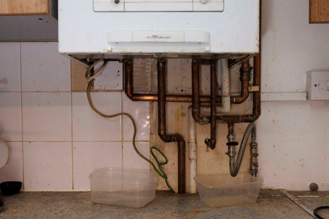 Inside the flat of Remi Olawe, 49, mother of five, which suffers from mould issues and has a broken boiler that the Housing Association has not been able to fix. Pictured: The boiler in question was working until the HA did a service on it which then broke it. Buckets are placed under it because water is leaking from beneath. (C) Belinda Jiao 07598931257 www.belindajiao.com jiao.bilin@gmail.com