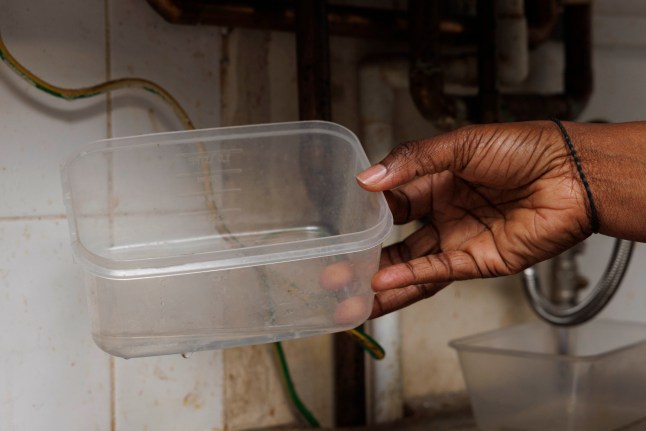 Inside the flat of Remi Olawe, 49, mother of five, which suffers from mould issues and has a broken boiler that the Housing Association has not been able to fix. Pictured: The boiler in question was working until the HA did a service on it which then broke it. Buckets are placed under it because water is leaking from beneath. (C) Belinda Jiao 07598931257 www.belindajiao.com jiao.bilin@gmail.com