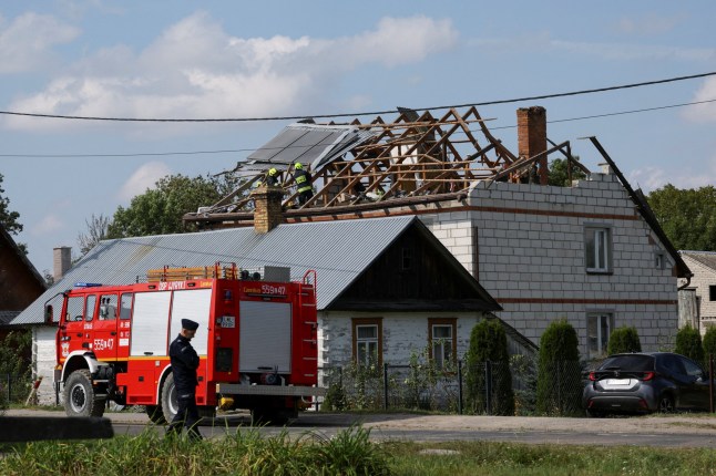 A police officer stands below as firefighters work on the destroyed roof of a house, after Russian drones violated Polish airspace during an attack on Ukraine, with some being shot down by Poland with the backing from its NATO allies, in Wyryki-Wola, Lublin Voivodeship, Poland, September 10, 2025. REUTERS/Kacper Pempel REFILE - CORRECTING LOCATION FROM "WYRYKI" TO "WYRYKI-WOLA" .