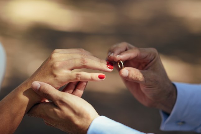 Groom putting wedding ring on finger of bride, close up