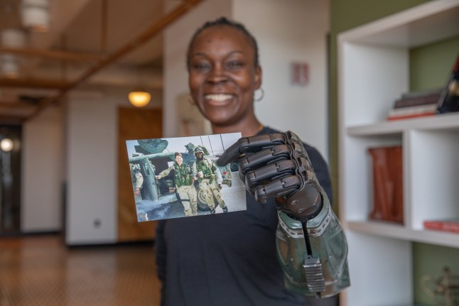Danielle Green uses her Hero RGD??? hand to hold a photo of herself from her U.S. Army deployment in Baghdad, Iraq, 2004, before the rocket-propelled grenade attack that claimed her left arm. A natural left-hander, she had to relearn everything from writing, to daily tasks. Her story of resilience continues to inspire combat veterans nationwide. A female US Army vet who nearly died in a grenade attack in Iraq has become the first in the world to be fitted with a new 'hero' bionic arm - inspired by Call of Duty.Danielle Green lost her left arm while serving in Baghdad 20 years ago and has struggled with every day tasks ever since.But now, in a world-first, the 48-year-old says she wants to inspire fellow vets and amputees - and finally feels 'complete' after being fitted with the Hero RGD.The rugged new limb, described as the world's stongest bionic arm, has been developed by UK robotics firm Open Bionics with a design inspired by the Call of Duty: Black Ops 7 game. Photo released 01/10/2025