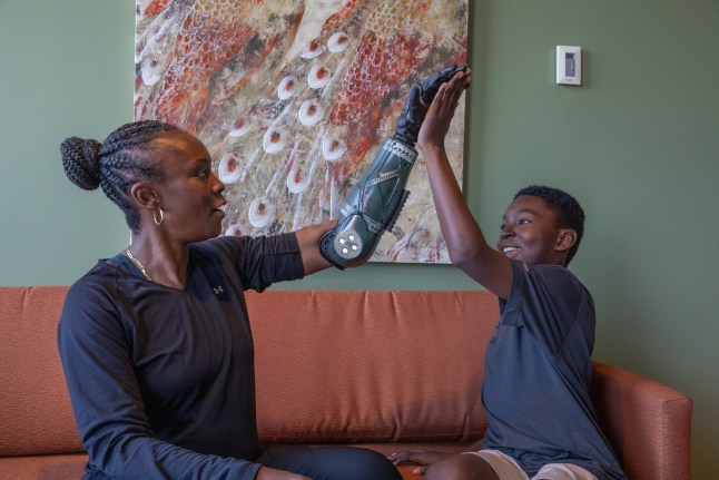 Danielle Green high-fives her son with the Hero RGD???, the world???s most rugged bionic arm from Open Bionics. Green is the first U.S. veteran to be fitted with the device, featuring custom covers designed with Call of Duty Endowment and debuted at Call of Duty NEXT 2025 in Las Vegas, September 30. A female US Army vet who nearly died in a grenade attack in Iraq has become the first in the world to be fitted with a new 'hero' bionic arm - inspired by Call of Duty.Danielle Green lost her left arm while serving in Baghdad 20 years ago and has struggled with every day tasks ever since.But now, in a world-first, the 48-year-old says she wants to inspire fellow vets and amputees - and finally feels 'complete' after being fitted with the Hero RGD.The rugged new limb, described as the world's stongest bionic arm, has been developed by UK robotics firm Open Bionics with a design inspired by the Call of Duty: Black Ops 7 game. Photo released 01/10/2025