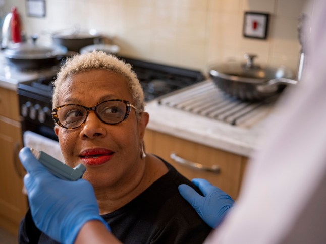 Nurse visiting mature woman at her house, administering medication