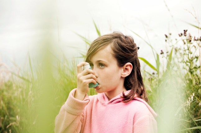 Girl (5-7) using asthma inhaler, Southwold, Suffolk, United Kingdom