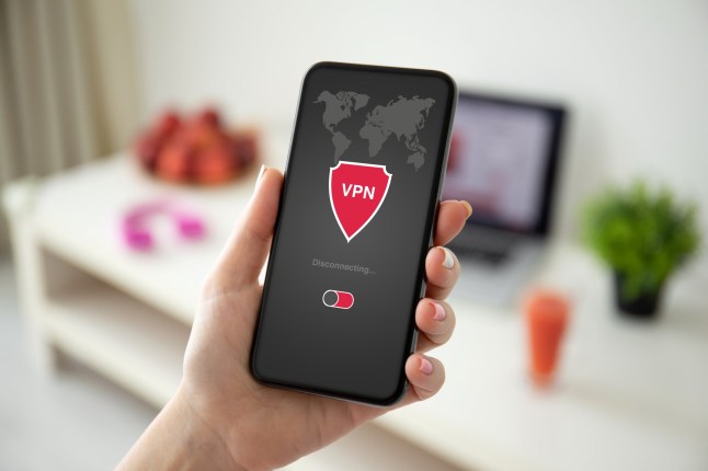 Female hand holding phone with app VPN creation Internet protocols for protection private network background room in the house