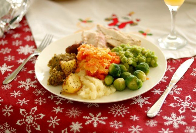 A Christmas dinner on a table with a glass of wine, cutlery and a festive tablecloth.