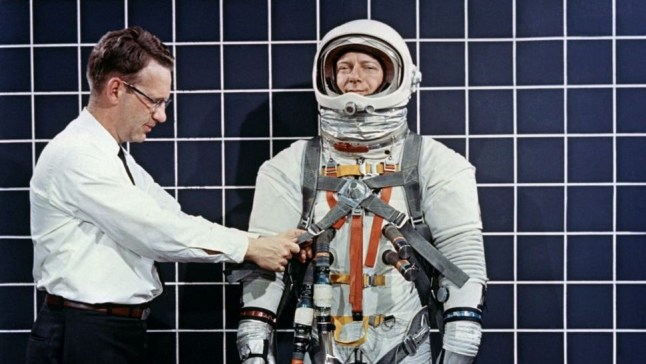 Engineer Bill Peterson fits test pilot Bob Smyth in an Apollo space suit with a Lunar Excursion Module restraint harness during suit testing in 1968.