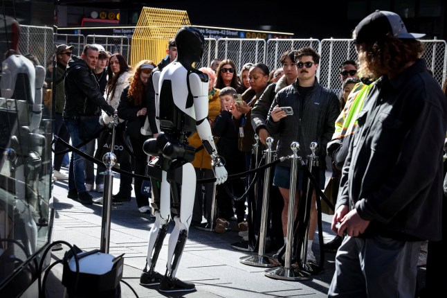 A crowd watches and interacts with a Tesla Optimus robot outside the Nasdaq Market site in New York City, U.S., October 27, 2025. REUTERS/Brendan McDermid