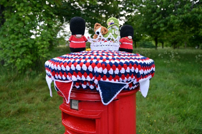 A knitted Queen Elizabeth II with a corgi and accompanying guards is pictured above a post box in Hangleton near Hove, East Sussex, on May 31, 2022 ahead of the Queen's Platinum Jubilee in England. - Britain is bringing out the bunting this week for Queen Elizabeth II's Platinum Jubilee, with four days of public events to mark her 70 years on the throne. (Photo by GLYN KIRK / AFP) (Photo by GLYN KIRK/AFP via Getty Images)