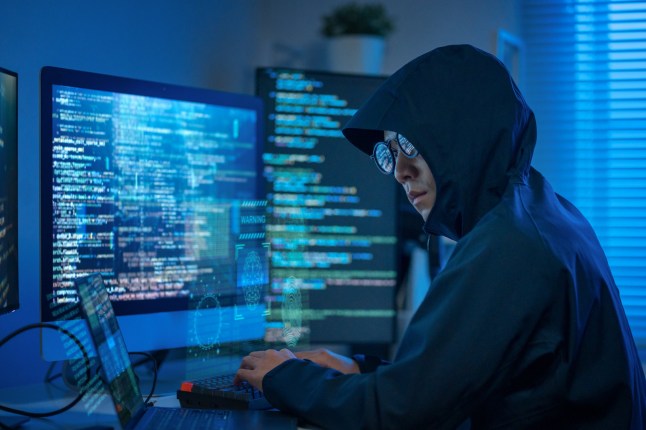 Multi-screen setup in a dark room, showing a hacker coding for identity theft and stealing data through the dark web.