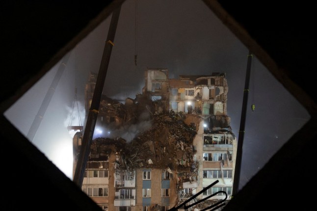 Rescuers clear debris at the site of an apartment building that was hit yesterday by a Russian missile