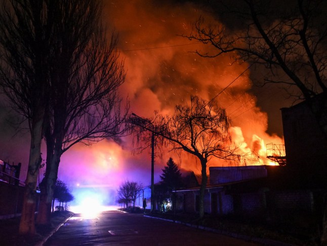 A resident stands on a street while buildings burn after an evening Russian drone strike, amid Russia's attack on Ukraine, in Zaporizhzhia, Ukraine November 25, 2025. REUTERS/Stringer