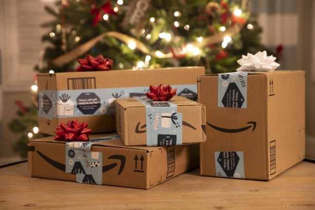 Mandatory Credit: Photo by Ruaridh Stewart/ZUMA Wire/Shutterstock (11549408p) Plain brown cardboard Amazon shipping boxes with amazon smile logo and Christmas holiday seasonal tape. The packages are placed like gifts under a Christmas tree. Due to coronavirus and Covid-19 ecommence, online shopping and shipping has exploded with a deluge of packages expected during the holiday season. Amazon alone has said it would hire 100,000 seasonal shipping workers. Amazon Holiday Shipping Boxes, Aliso Viejo, California, USA - 14 Dec 2020