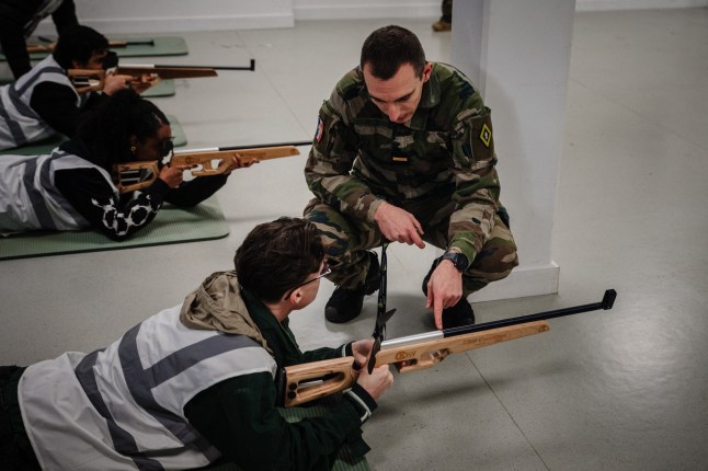 A military instructor provides guidance to participants during a laser shooting training session as part of the Defense and Citizenship Day (JDC) at Fort de Montrouge in Arcueil, south of Paris, November 26, 2025. President Emmanuel Macron is set to announce that France is restoring military service on a voluntary basis in the face of the growing threat posed by Russia, just under three decades after compulsory national service was abolished in the country and replaced by the JDC. (Photo by Dimitar DILKOFF / AFP via Getty Images)