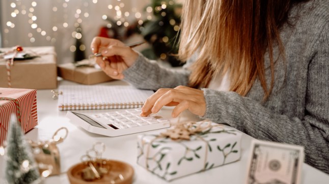 Girl counting US Dollar bills, using calculator, and writing expenses. Woman doing budget, estimating money balance for shopping spree. Female accountant paying taxes. Girl counting Christmas gifts
